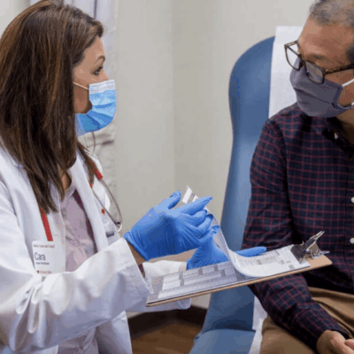 A doctor talking to a patient wearing a mask.
