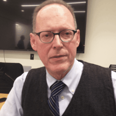 A man wearing glasses and a vest.