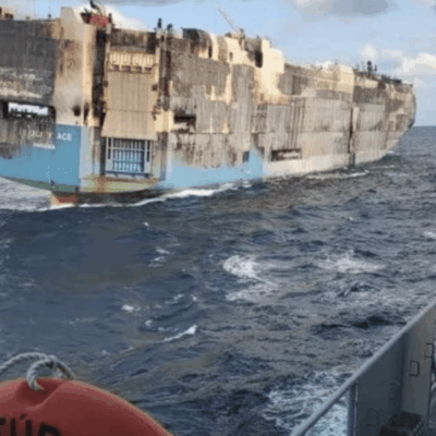 A ship in the ocean with a red flag on it.