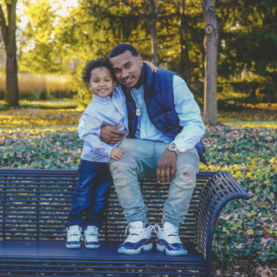A man and his son sitting on a bench in a park.