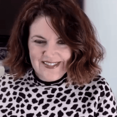 A woman in a leopard print shirt is smiling.