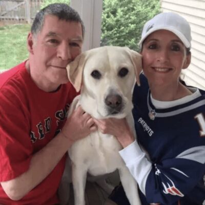A man and woman pose for a photo with their dog.