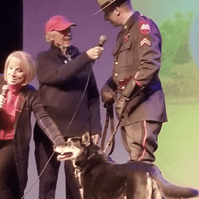 A man in a police uniform with a dog on stage.