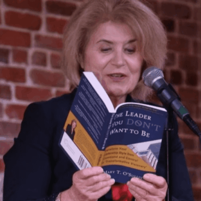 A woman reading a book into a microphone.