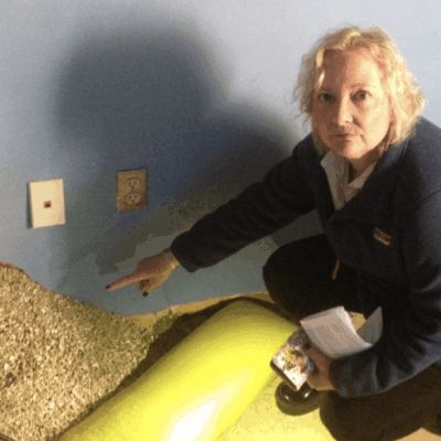 A woman kneeling down in a room with a bag of sand.