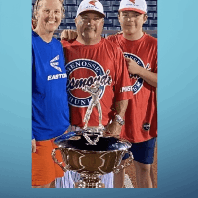 A family is posing with a trophy on a baseball field.