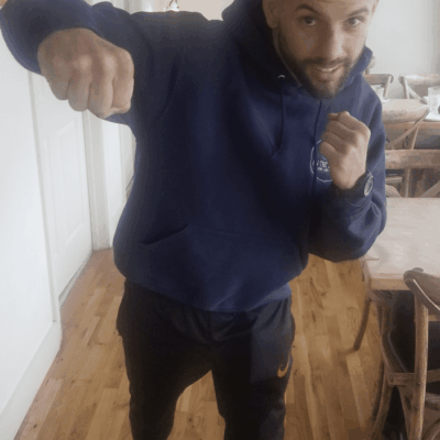 A man in a blue hoodie is posing for the camera.