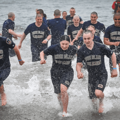 A group of people running through the water.