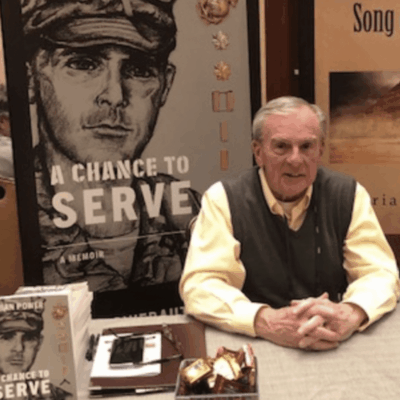 A man sitting at a table with a book in front of him.