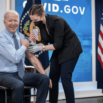 Joe biden getting a vaccine in front of an american flag.