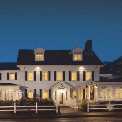 A white house at night with a white picket fence.