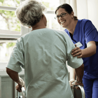 A nurse is helping an elderly woman with a walker.