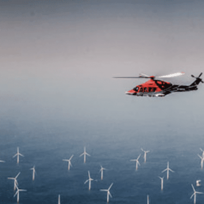 A helicopter flying over wind turbines.