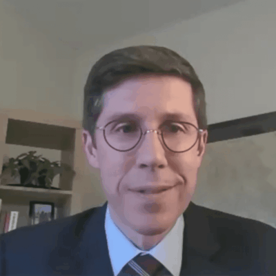 A man in a suit and tie is talking on a video.