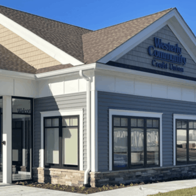 The front of a building with gray siding and a blue roof.