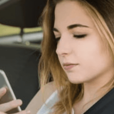 A woman using her cell phone in a car.