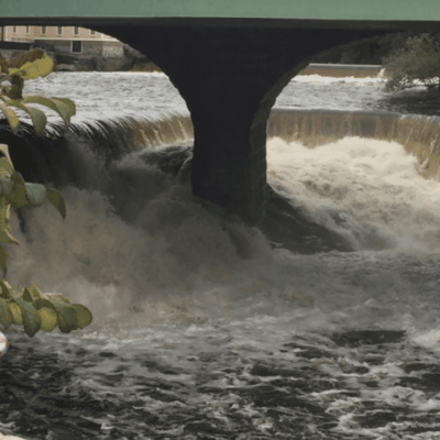 A hat with an american flag on it sits next to a waterfall.