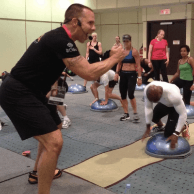A group of people in a gym doing squats and push ups.