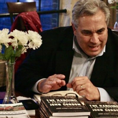A man sitting at a table signing books.