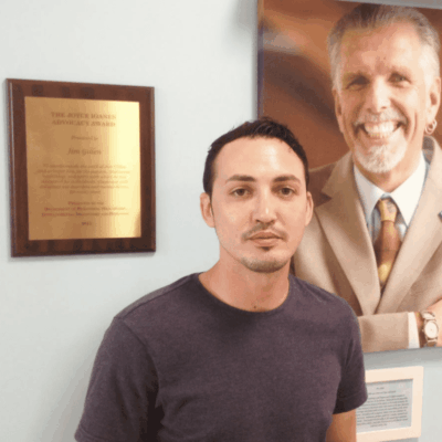 A man standing in front of a wall with a picture of an old man.