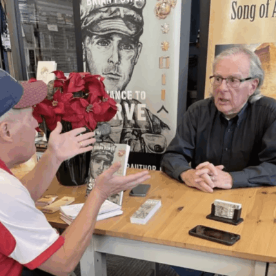 Two men sitting at a table talking to each other.