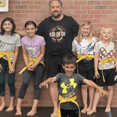 A group of children posing for a photo with a karate instructor.