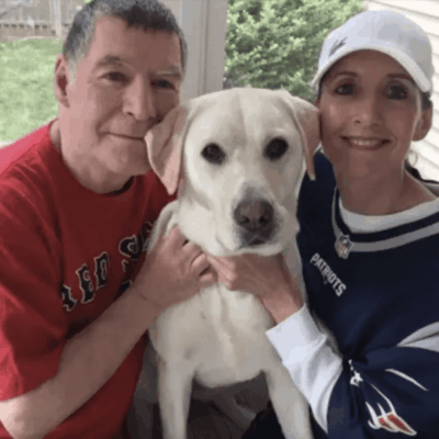 A man and woman pose for a photo with their dog.
