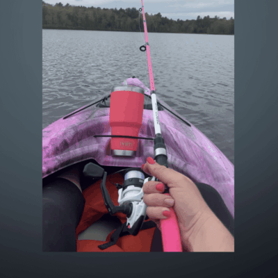 A person holding a pink fishing rod in a kayak.