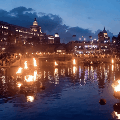 A large group of people watching a fire in a pond.