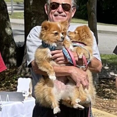 A man holding two small dogs at an event.