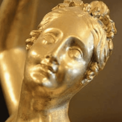 A close up of a gold statue of a woman.