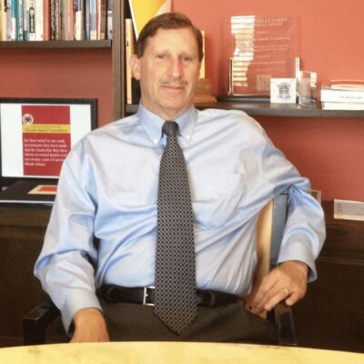 A man in a blue shirt sitting at a desk.
