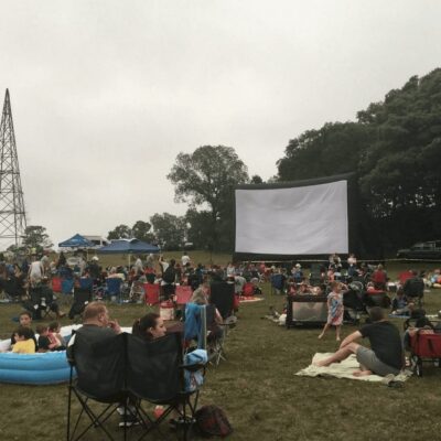 A group of people watching a movie in a field.