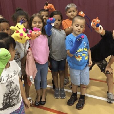 A group of children are posing with puppets.