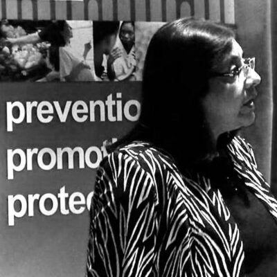 A woman standing in front of a poster with the words prevention promoted protection.