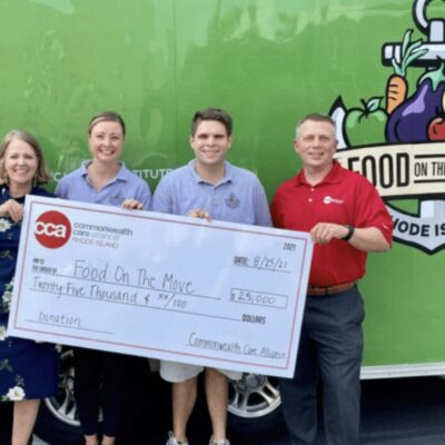 A group of people standing in front of a food truck with a check.