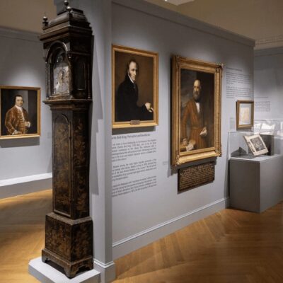 A room with paintings and a clock on display.