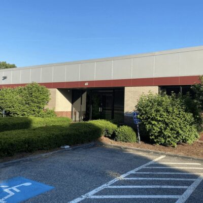 A building with a parking lot and bushes.