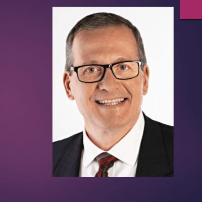 An image of a man with glasses and a purple background.