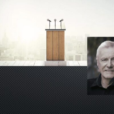 A photo of a man with a podium in front of a city.