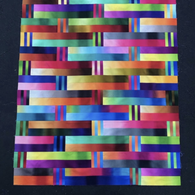 A quilt with colorful strips on a black background.