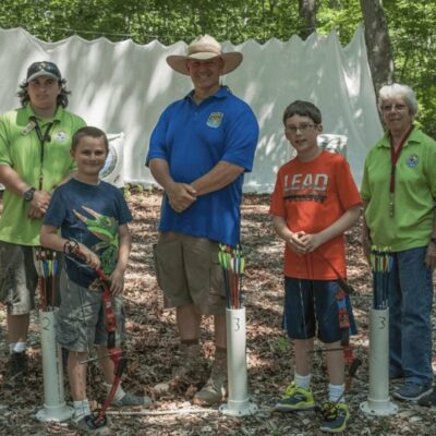 A group of people posing for a picture in the woods.