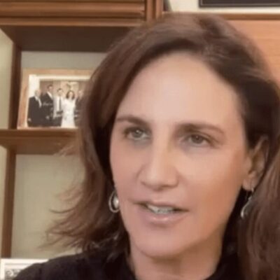 A woman in a black shirt is talking to the camera.