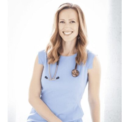 A smiling woman in a blue dress with a stethoscope.