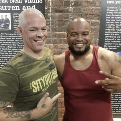 Two men posing for a photo in front of a wall.