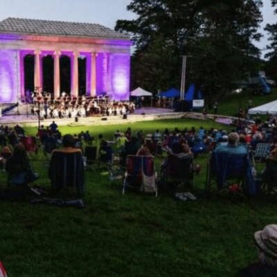 A group of people sitting on lawn chairs at a concert.