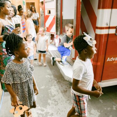 A group of children standing in front of a fire truck.