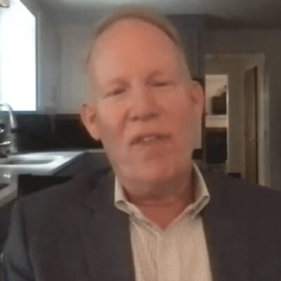 A man in a suit sitting in a kitchen.