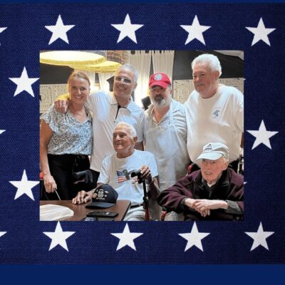 A group of people posing in front of an american flag.
