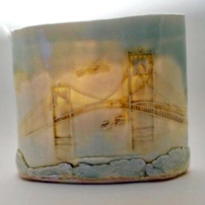 A ceramic mug with a drawing of a bridge.